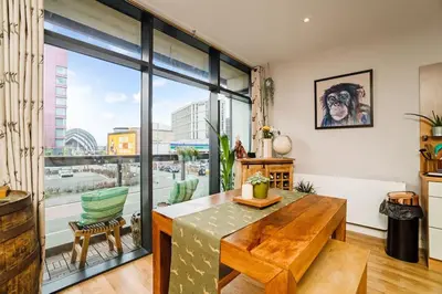 a living room with a table and a large window at Luxury Huge Modern Open Plan 2Bedroom Flat - Free Private Parking & Balcony located at the OVO Hydro and SEC Centre in Glasgow