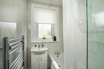 a white bathroom with a sink and a shower at Free Parking - 2 Bedroom Flat-by Holiday Homes in Cambusnethan
