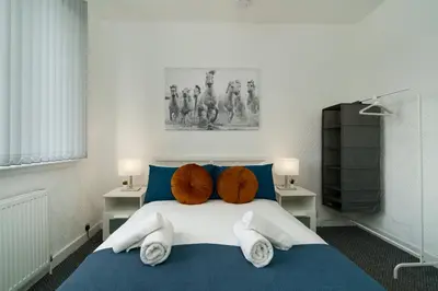 a bedroom with a blue and white bed with pillows at Free Parking - 2 Bedroom Flat-by Holiday Homes in Cambusnethan