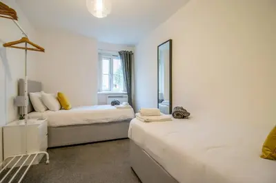 a white room with two beds and a mirror at 2 bed flat near airport &parking in Paisley