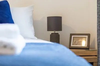 a bedroom with a bed with a lamp and a picture at 2 bed flat near airport &parking in Paisley