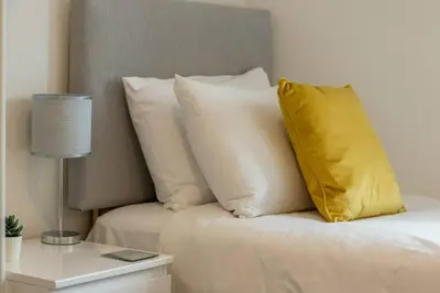 a yellow pillow sitting on top of a bed with pillows at 2 bed flat near airport &parking in Paisley