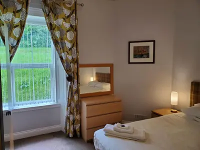 a bedroom with a mirror and a bed and a window at McCaig's View in Oban
