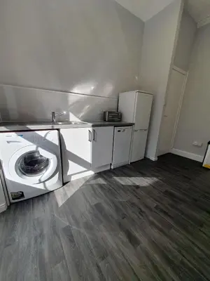 a laundry room with a washer and a refrigerator at McCaig's View in Oban