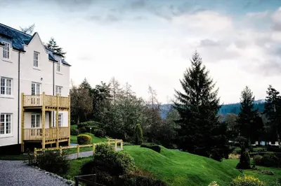 a house on a hill with a green yard at Macdonald Forest Hills Hotel & Spa in Aberfoyle