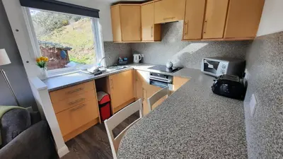 a small kitchen with wooden cabinets and a window at Skye in Oban