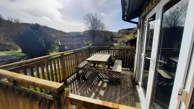 a wooden deck with a picnic table on a balcony at Skye in Oban