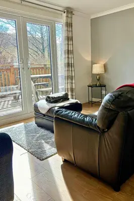 a living room with a leather couch and a balcony at Rum in Oban
