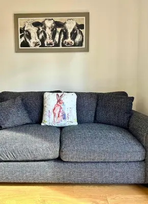 a blue couch in a living room with a picture of cows at Rum in Oban