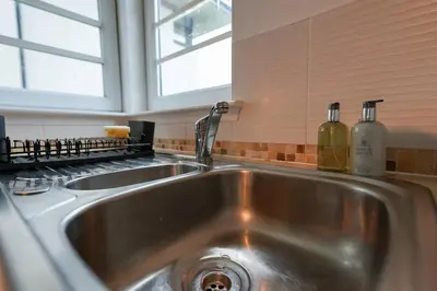 a stainless steel kitchen sink with two bottles on it at Whiteside Apartment in Bathgate