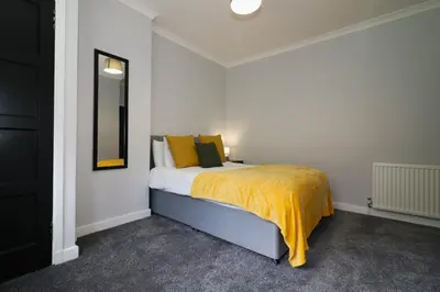 a bedroom with a bed with a yellow blanket at Signature - Huntley House in Glasgow
