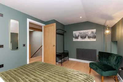 a bedroom with a green bed and a chair at Dragon Suites - City Centre 2 Bed Luxury Mews House in Edinburgh
