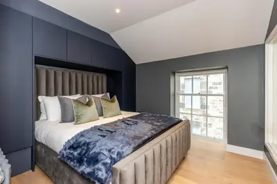 a bedroom with a large bed with blue walls at Dragon Suites - City Centre 2 Bed Luxury Mews House in Edinburgh