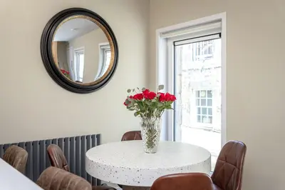 a white table with a vase of flowers on it at Dragon Suites - City Centre 2 Bed Luxury Mews House in Edinburgh