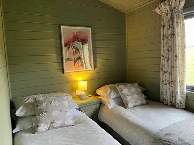 two beds in a room with green siding at The Lodge at Blackhill Farm in Carluke