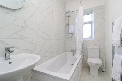 a white bathroom with a tub and a sink and a toilet at Meadowfoot Haven in West Kilbride