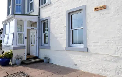 a white building with a door and windows at Janeville Holiday Apartment in Ardrishaig
