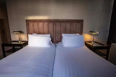 a bedroom with two beds with white sheets and two lamps at Strathaven Hotel in Strathaven