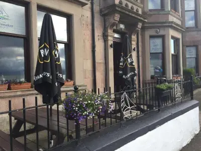 a restaurant with umbrellas and flowers in front of a fence at The Spinnaker Hotel in Gourock