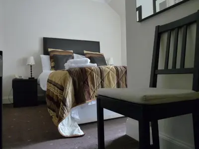 a bedroom with a bed and a chair and a bath tub at The Spinnaker Hotel in Gourock