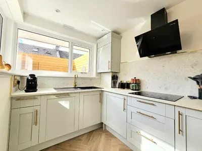 a kitchen with white cabinets and a flat screen tv at Newly Renovated Gem - Free Parking & Modern Comfort in Glasgow
