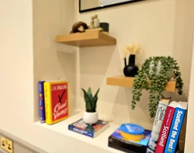 a shelf with books and a plant on it at Newly Renovated Gem - Free Parking & Modern Comfort in Glasgow