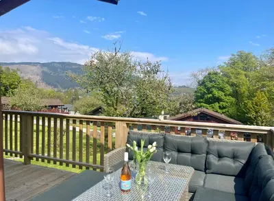a patio with a couch and a table on a deck at Harris's Cabin in Hunters Quay