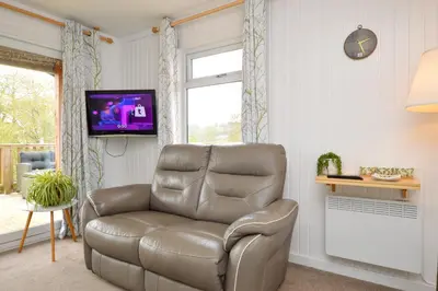 a leather reclining chair in a living room with a television at Harris's Cabin in Hunters Quay