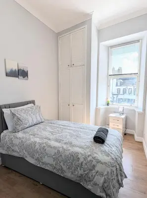 a white bedroom with a bed and a window at Campbeltown Central in Campbeltown