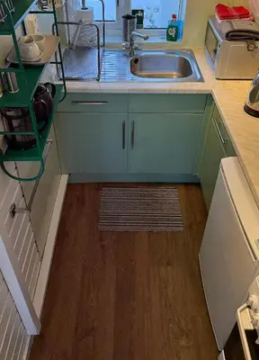 a kitchen with a sink and a wooden floor at 1 Bedroom Cabin with Mountain & Loch Views - Quiet Location between Glencoe & Ben Nevis in Onich