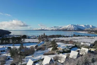an aerial view of a town with snow covered mountains at 1 Bedroom Cabin with Mountain & Loch Views - Quiet Location between Glencoe & Ben Nevis in Onich