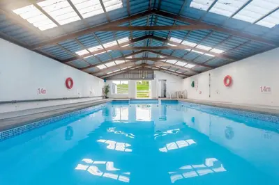 a large indoor swimming pool with blue water at Courtyard Cottages, Barn Cottage in Wigtown