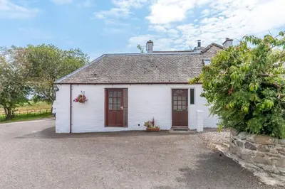 a small white house with red doors on a street at Courtyard Cottages, Garden Cottage in Wigtown
