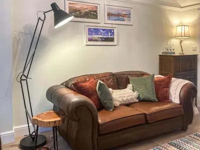 a living room with a brown leather couch with pillows at Darroch in Moniaive