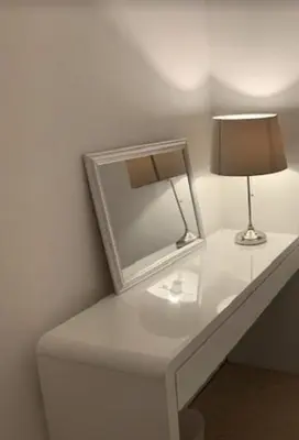 a white table with a mirror and a lamp on it at airport appartment in Paisley