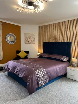 a bedroom with a large bed and a chandelier at The Rest in Tarbert