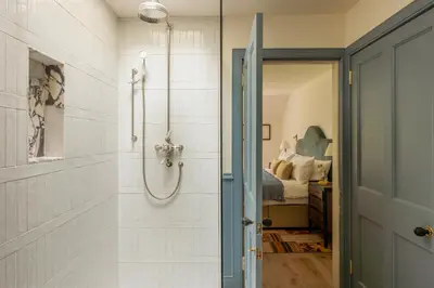 a bathroom with a walk in shower next to a bed at Penicuik Estate in Penicuik