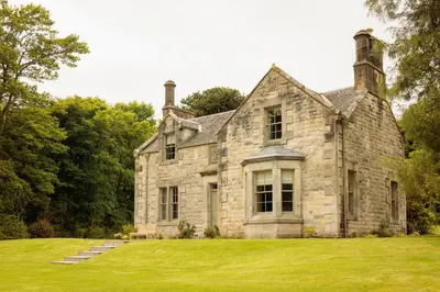 an old stone house with a green lawn at Penicuik Estate in Penicuik