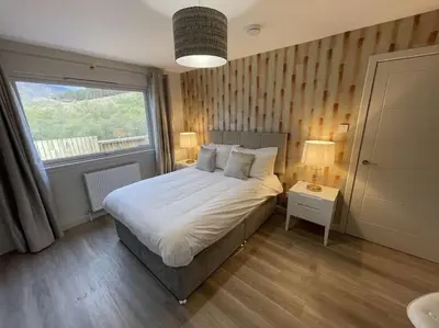 a bedroom with a large bed and a window at Hot tub lodge with stunning view in Taynuilt