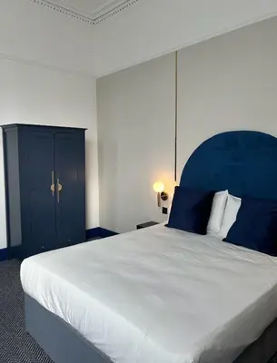 a bedroom with a large bed with a blue headboard at Hotel Baba in Uddingston