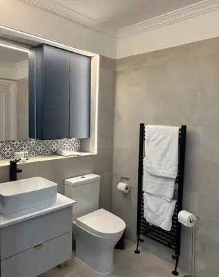a bathroom with a toilet and a sink and a mirror at Hotel Baba in Uddingston
