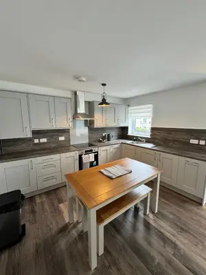 a kitchen with white cabinets and a wooden table at Inchtavannach Apartment 1/1 in Bonhill