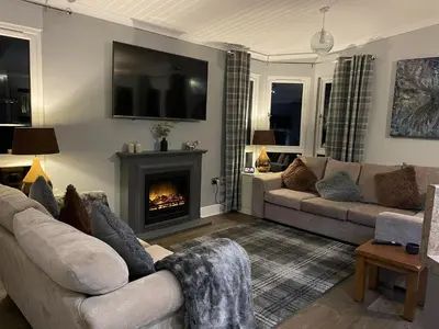 a living room with a couch and a fireplace at Riverbank Lodge in Dollar