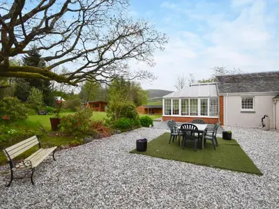 a patio with a table and chairs and a building at Nether Auchlinsky Cottage in Glendevon