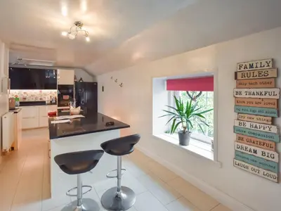a kitchen with black counter stools and a window at Nether Auchlinsky Cottage in Glendevon