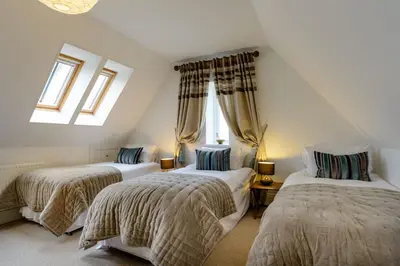 a attic room with two beds and two windows at Alexander House 24 - Self Catering in Auchterarder