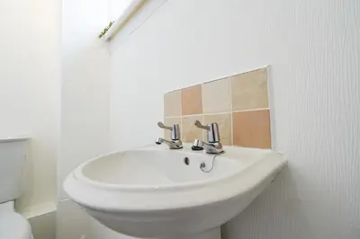 a white sink in a bathroom with a tiled wall at Livingston 4 Bed + Car Space in Livingston