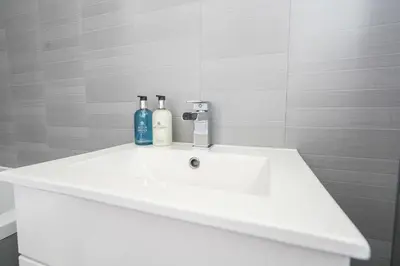 a white bathroom sink with two bottles on it at Livingston 4 Bed + Car Space in Livingston