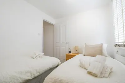 a white bedroom with two beds and a window at Livingston 4 Bed + Car Space in Livingston