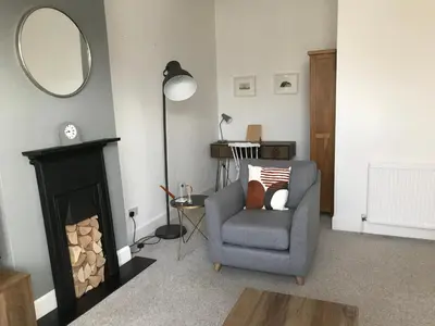 a living room with a chair and a mirror at Caerlaverock Cottage in Prestwick